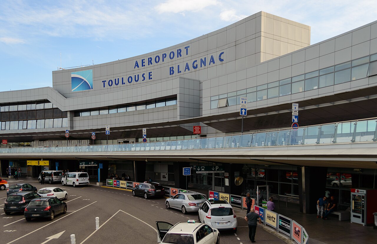 Aérogare de Toulouse-Blagnac, enseigne AEROPORT, voies de dépose et comptoirs de location.