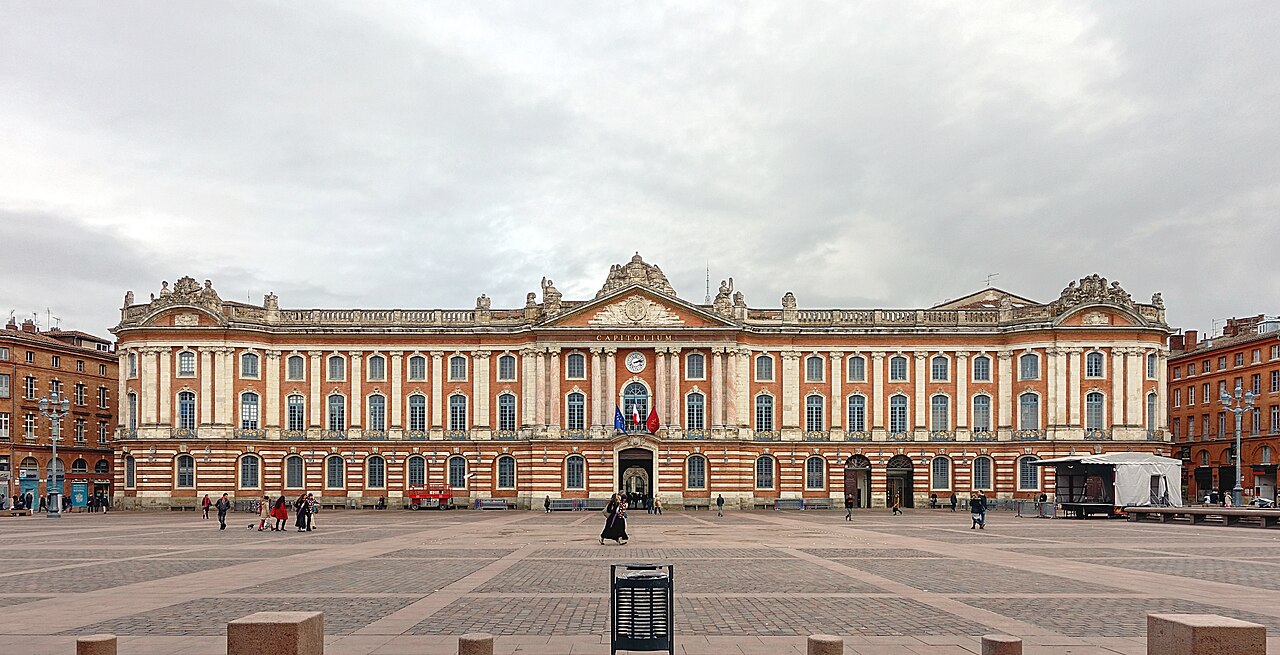 Façade néoclassique du Capitole de Toulouse, brique et pierre, inscription CAPITOLIUM, place dallée sous ciel couvert.